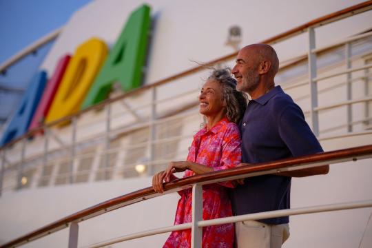 Mann und Frau stehen an Reling auf einem Kreuzfahrtschiff von AIDA